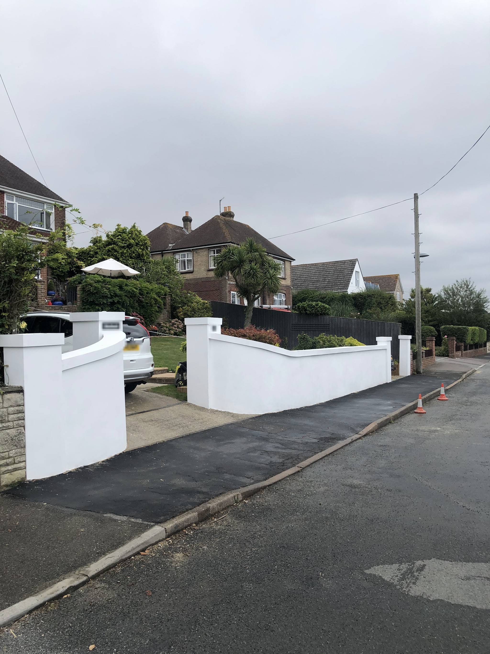Freshly rendered white front garden walls and pillars with a curved wall