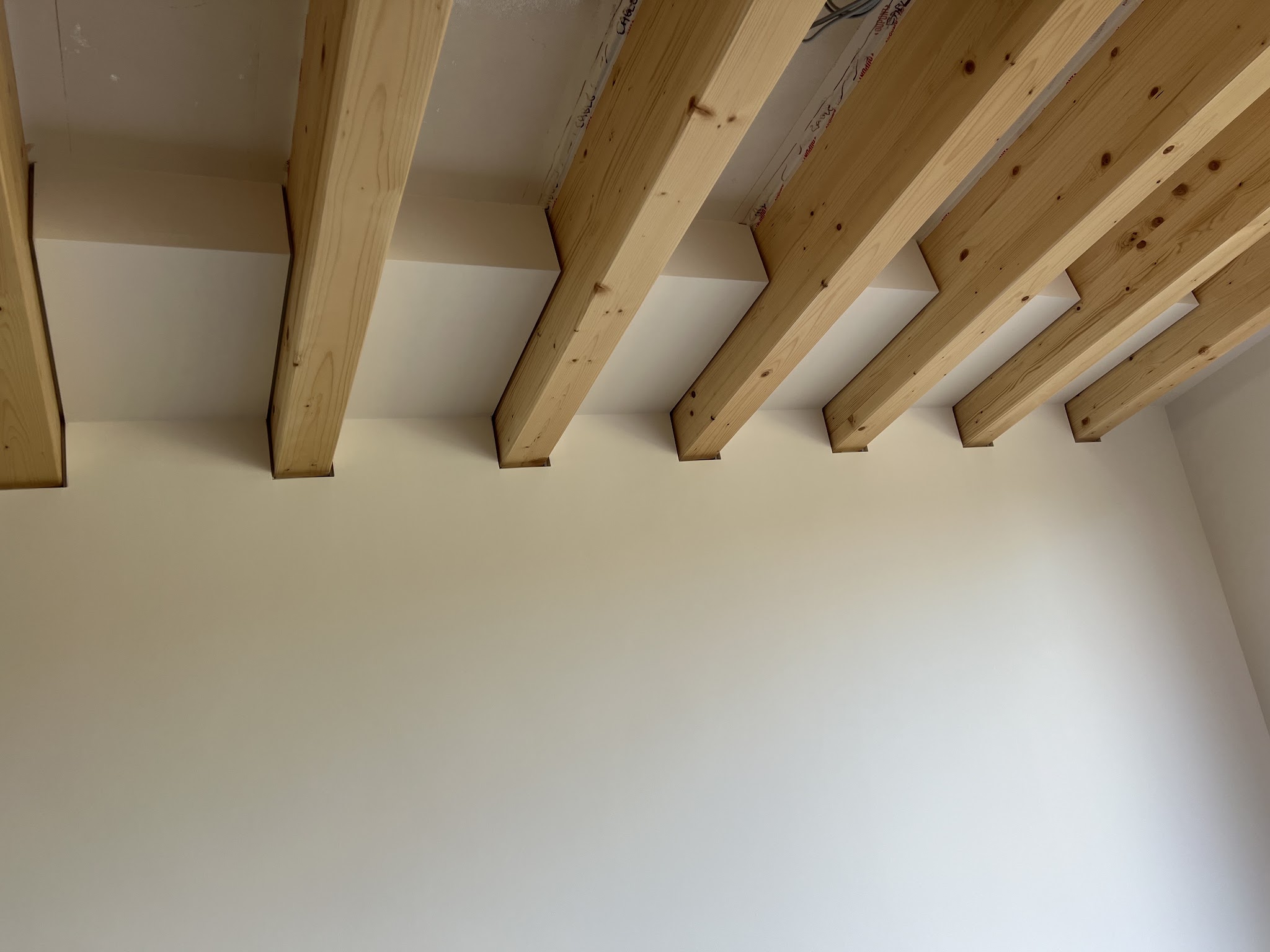 A ceiling freshly plastered between exposed timber beams