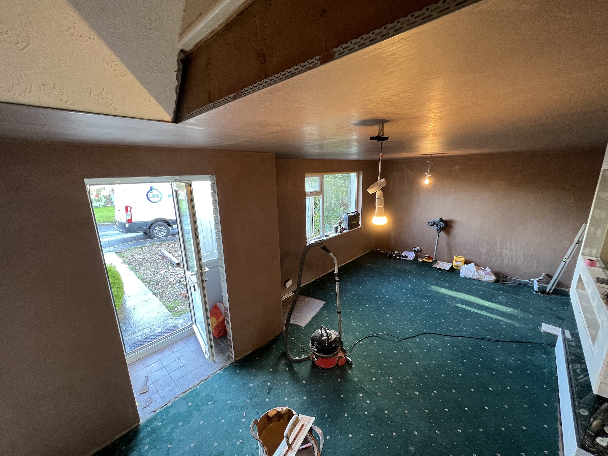 A room freshly plastered, seen from the stairs, with the garden door open