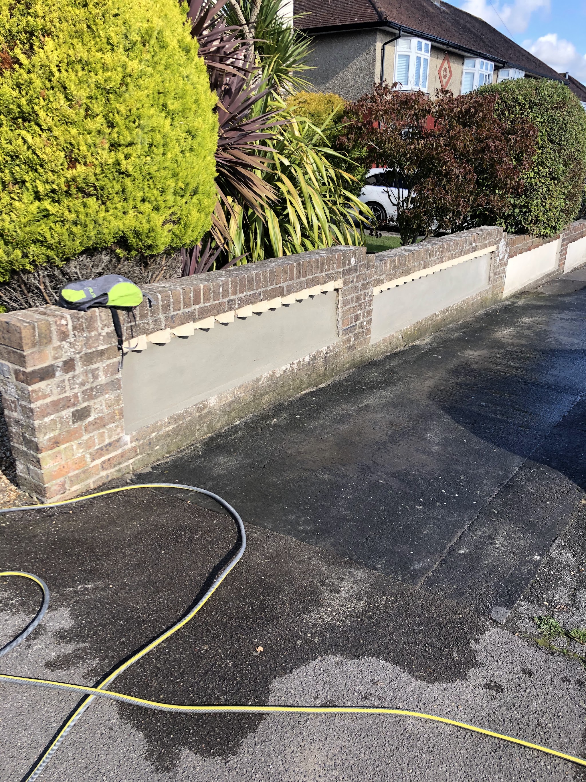 Rendered panels set into a brick front garden wall beside a drive